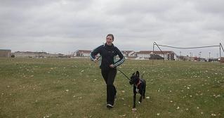 Woman and black lab mix running in field