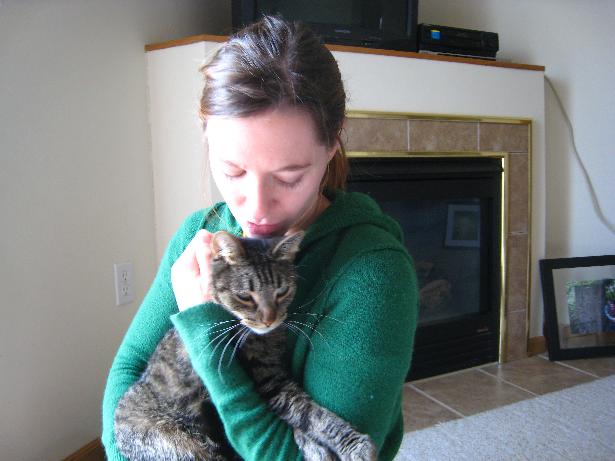Should a cat be declawed? Woman holding her gray tabby cat hugging him